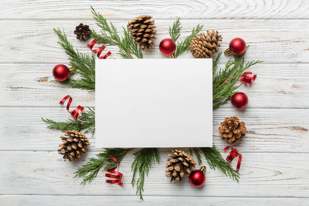 Flat lay Christmas composition. square Paper blank, pine tree branches, christmas decorations on Colored background. Top view, copy space for text. - Photo, Image