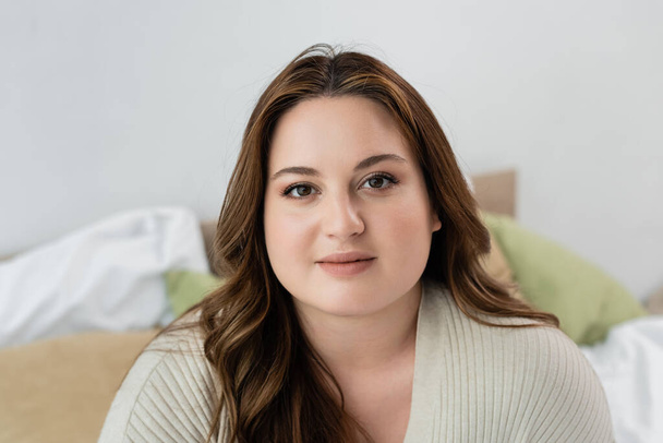 Pretty body positive woman looking at camera in bedroom  - Photo, Image