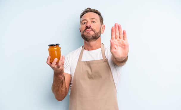 middle age handsome man looking serious showing open palm making stop gesture. peach jam concept - Valokuva, kuva