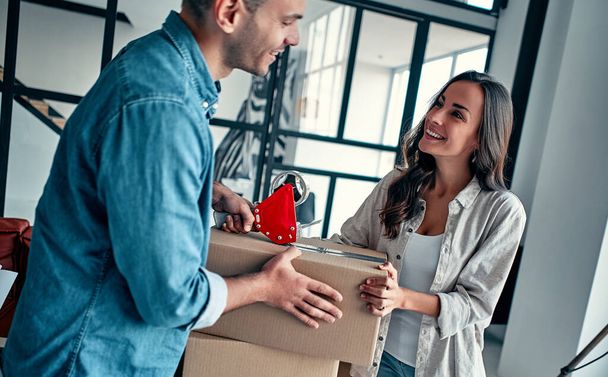 Jeune couple caucasien emballage boîte en carton pour se déplacer dans un nouvel appartement. - Photo, image