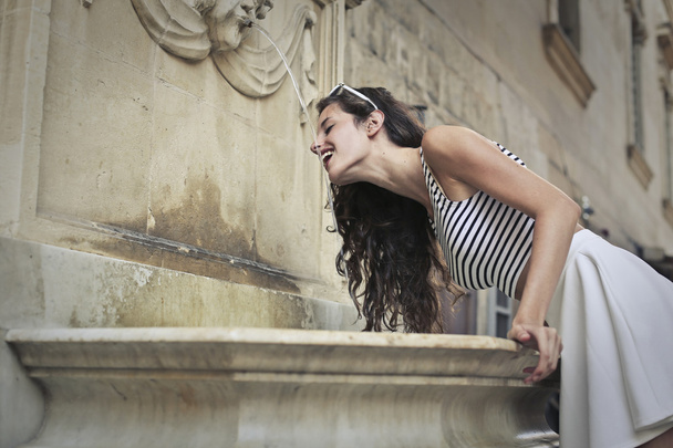 Young thirsty girl drinking water from a fountain - Foto, Imagem