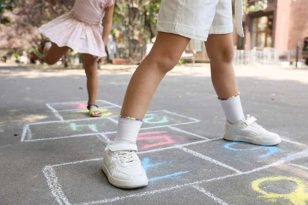 Little children playing hopscotch drawn with chalk on asphalt outdoors, closeup - 写真・画像
