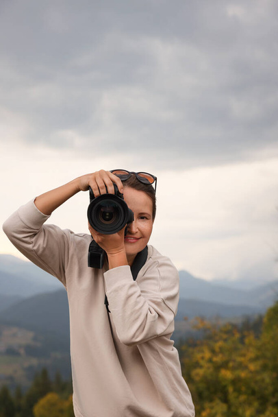 Professional photographer taking picture with modern camera in mountains - Foto, Imagem