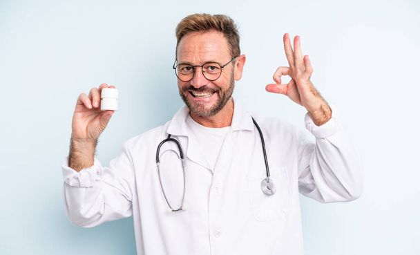 middle age handsome man feeling happy, showing approval with okay gesture. physician with pills bottle - Photo, Image
