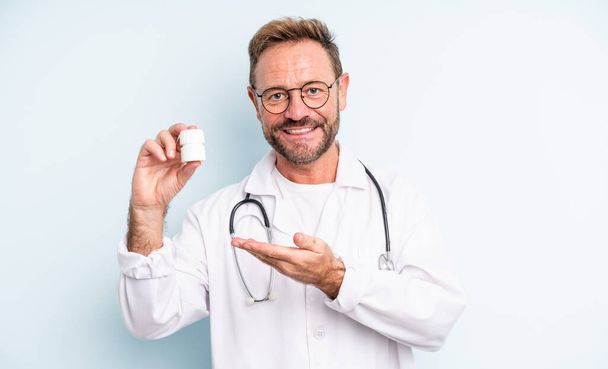 middle age handsome man smiling cheerfully, feeling happy and showing a concept. physician with pills bottle - Фото, зображення