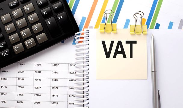 Tekst VAT, napisany na naklejce z kalkulatorem, pióro na tle mapy. - Zdjęcie, obraz