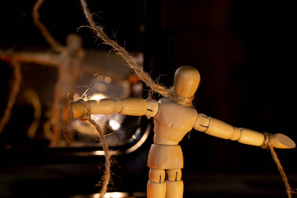 деревянный человек на веревках, привязанных к человеческой руке, манипулирующий людьми и рабством, свободная воля, власть над людьми - Фото, изображение