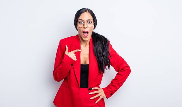 pretty hispanic woman looking shocked and surprised with mouth wide open, pointing to self. businesswoman concept - Фото, изображение