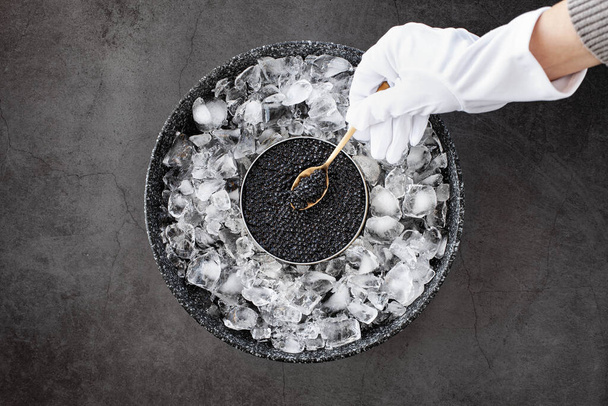 hand of waiter in gloves take a black caviar in spoon - Valokuva, kuva