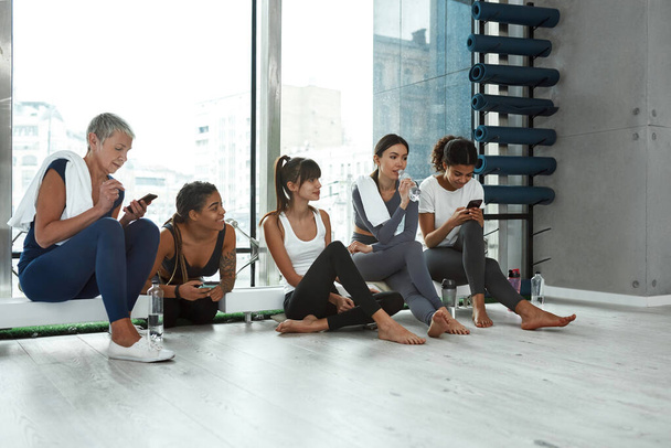 Active diverse women relax after workout in fitness club - Photo, image