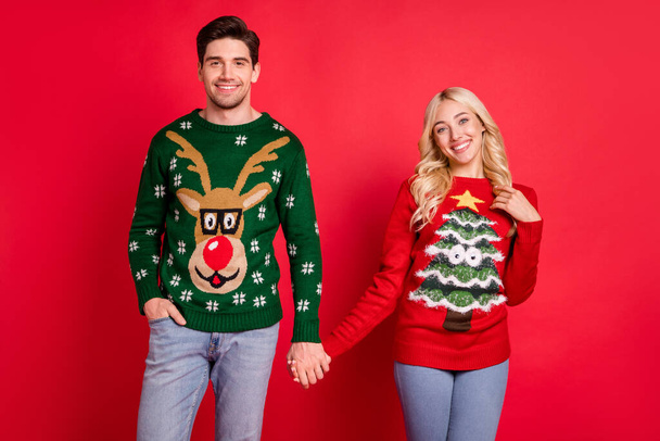 Photo of peaceful serene glad couple hold hands wear ugly ornament pullover isolated red color background - Fotoğraf, Görsel