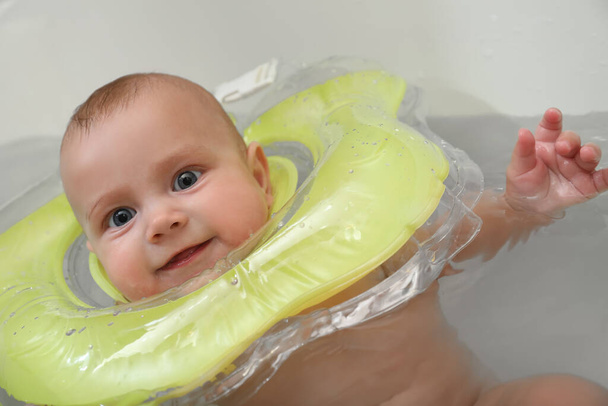 Cute little baby swimming with inflatable ring in bath - Фото, изображение