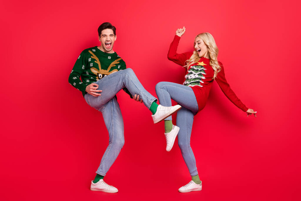 Photo of crazy careless couple dance celebrate scream wear ugly sweater jeans shoes isolated red color background - Φωτογραφία, εικόνα