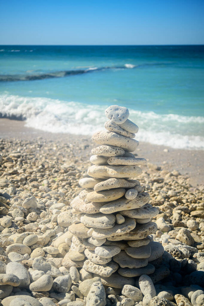 Stos kamienia na plaży na latarni morskiej Phare des Baleines na wyspie Ile de Re we Francji w słoneczny letni dzień - Zdjęcie, obraz