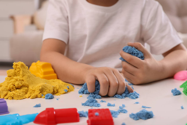 Little boy playing with bright kinetic sand at table indoors, closeup - Zdjęcie, obraz
