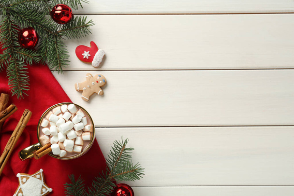 Pyszna gorąca czekolada z piankami w pobliżu ciasteczek i świąteczny wystrój na białym drewnianym stole, płaski leżak. Miejsce na tekst - Zdjęcie, obraz