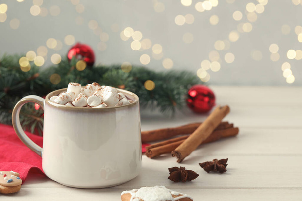 Delicious hot chocolate with marshmallows and Christmas decor on white wooden table, space for text - Fotografie, Obrázek