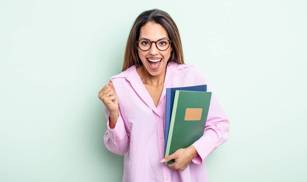 pretty hispanic woman feeling shocked,laughing and celebrating success. notebooks concept - Foto, Imagem
