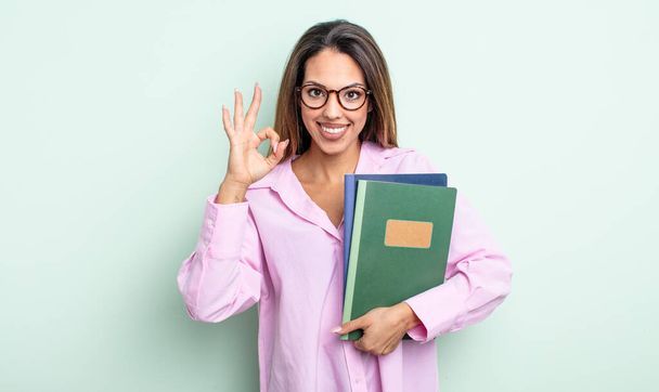 una mujer bastante hispana sintiéndose feliz, mostrando su aprobación con un buen gesto. concepto de cuadernos - Foto, Imagen