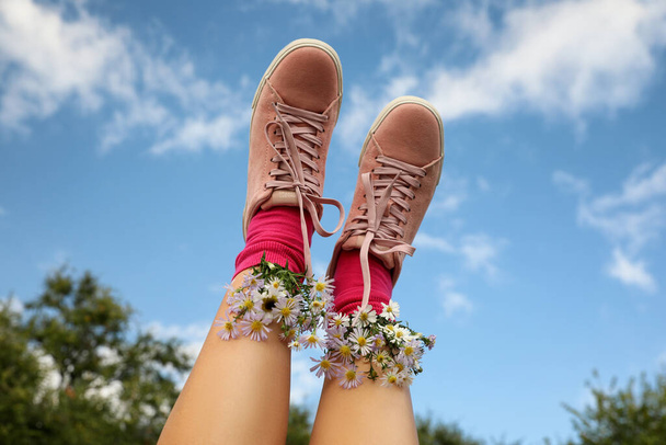 Woman with beautiful tender flowers in socks against blue sky, closeup - Photo, Image