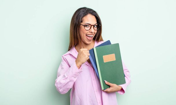 pretty hispanic woman feeling happy and facing a challenge or celebrating. notebooks concept - Photo, Image