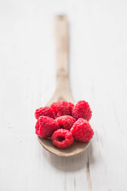 Raspberries in wooden spoon on white background - 写真・画像