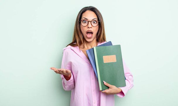 pretty hispanic woman feeling extremely shocked and surprised. notebooks concept - Photo, image