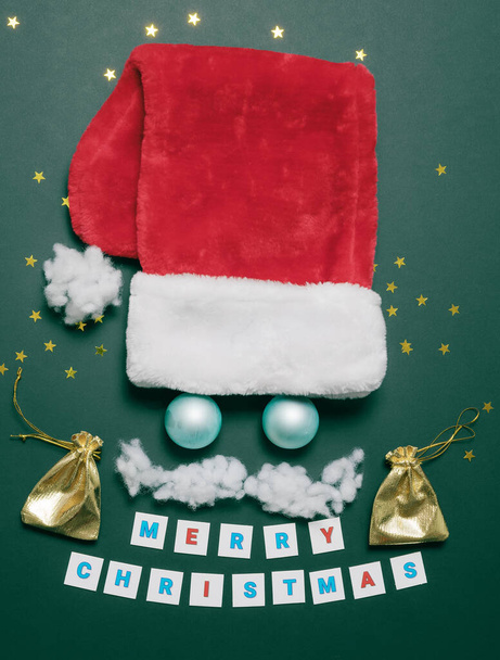 Funny Santas face with wadded mustache eyes from balls and with a red cap. Christmas card. Flatlay composition - Photo, Image