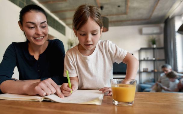 Small 7s girl child do homework with mom - Foto, immagini