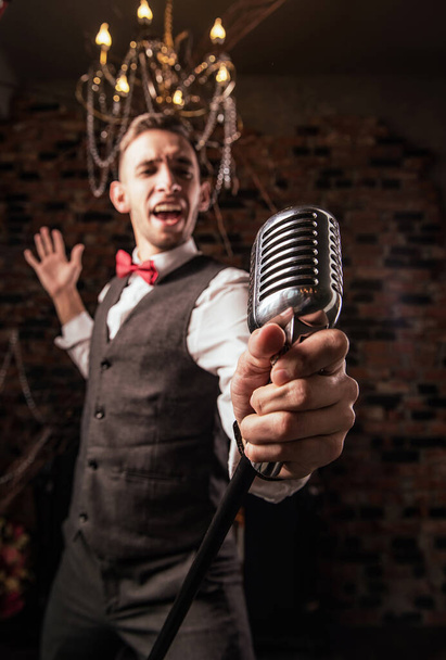 молодий чоловік з мікрофоном співає на вечірці
 - Фото, зображення