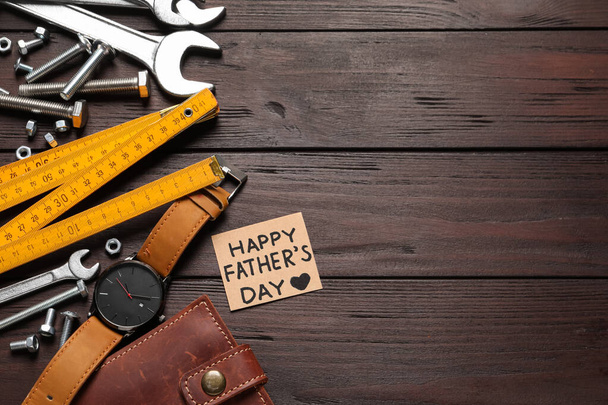 Card with phrase HAPPY FATHER'S DAY, different tools and male accessories on wooden background, flat lay. Space for text - Photo, image