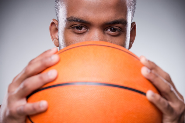 Αφρικής άνδρας που κρύβει το πρόσωπο πίσω από την μπάλα του μπάσκετ - Φωτογραφία, εικόνα