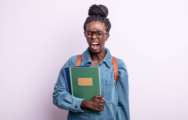 pretty black woman shouting aggressively, looking very angry. student with books concept - Fotografie, Obrázek