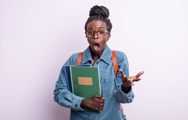 pretty black woman amazed, shocked and astonished with an unbelievable surprise. student with books concept - Φωτογραφία, εικόνα