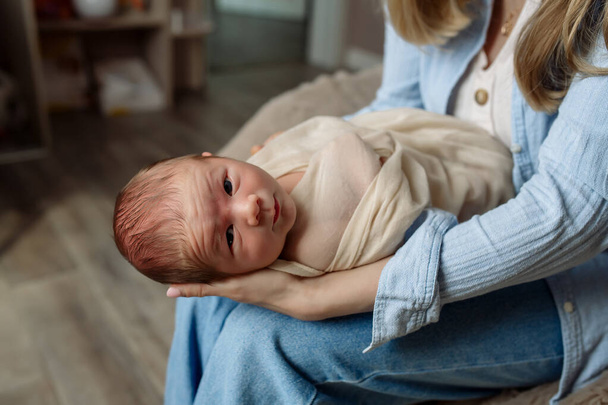 Giovane bella madre con i capelli lunghi tiene un neonato tra le braccia - Foto, immagini