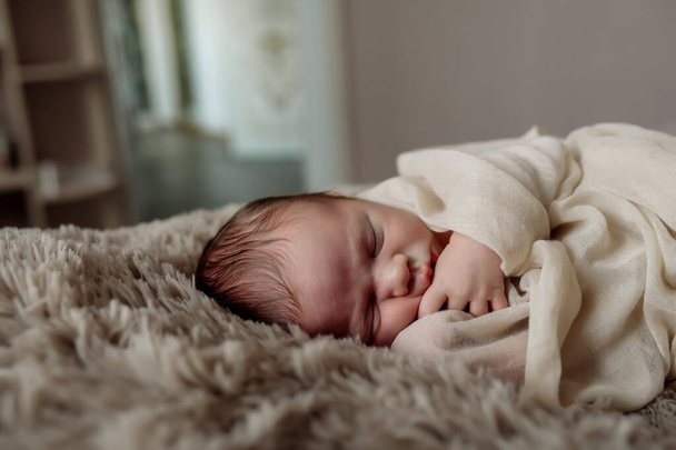 Little newborn baby sleeping on the bed in the bedroom, lulled by mom - Foto, afbeelding