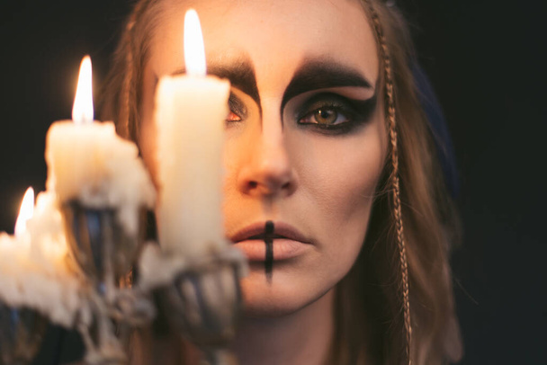 portrait of a witch with candle. Halloween mystical atmosphere. Celtic mythology goddess Valkyrie. Spiritualism spell rite. Masquerade makeup costume. Magic witchcraft occultism. Mystic mood lifestyle - Foto, Imagen