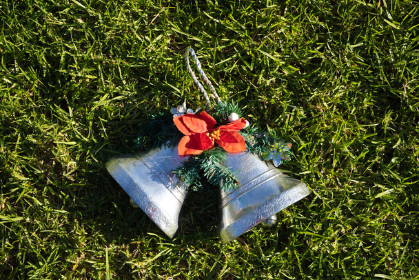 Weihnachtsdekoration, zwei silberne Glocken mit Weihnachtsstern auf dem Rasen des Gartens. Frohe Weihnachten - Foto, Bild