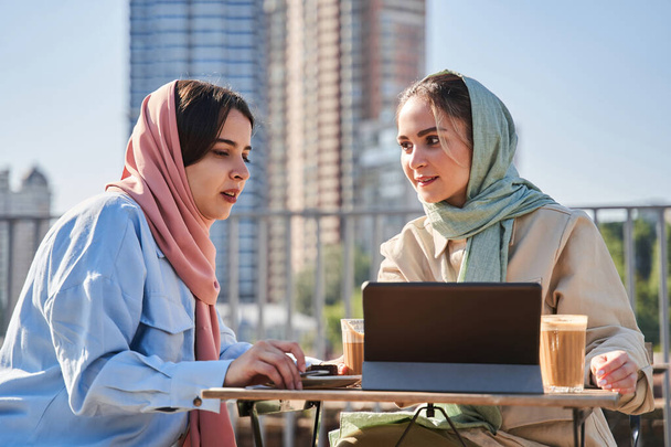 Girls wearing hijab using tablet computer and discussing something while working - Valokuva, kuva