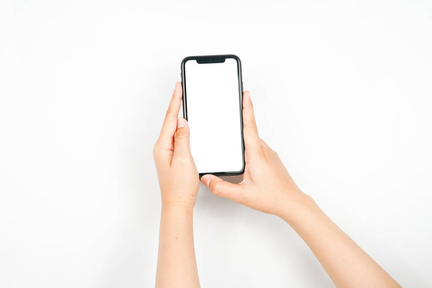 ein Smartphone mit zwei Händen halten. ein Smartphone mit einem leeren weißen Bildschirm, der für Werbeattrappen verwendet wird. - Foto, Bild