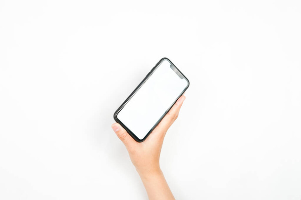 dłoń trzymająca przechylony smartfon. smartfon z białym ekranem służącym do modelowania reklam. - Zdjęcie, obraz