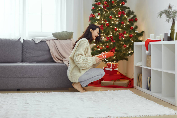 Woman With Present in the Gift Box Near Christmas Tree at Home - Фото, зображення