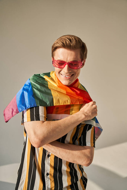 Young man with pride movement LGBT Rainbow flag on his shoulders - Fotó, kép