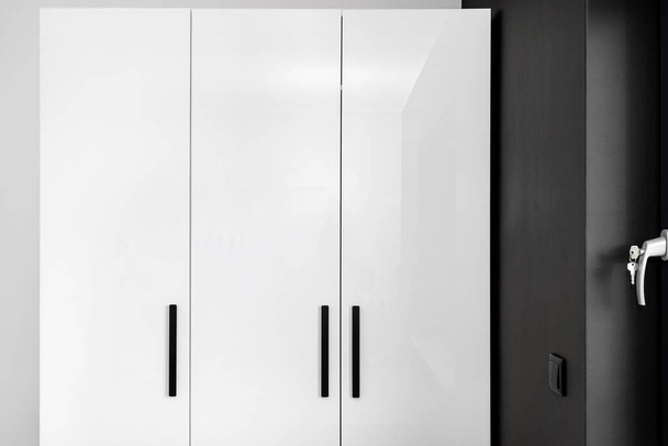 Large and high wardrobe in the bedroom with white fronts and black handles. - Photo, Image