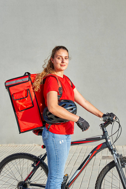 Portret van een fietser levering meisje op zoek naar camera - Foto, afbeelding