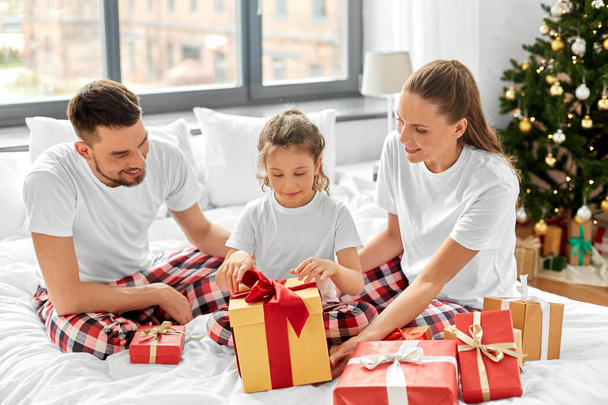 happy family with christmas gifts in bed at home - Fotó, kép
