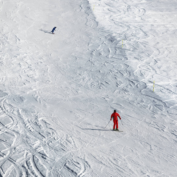 Skier and snowboarder downhill on snowy ski slope at sun winter day. Georgia, region Gudauri. Caucasus Mountains. - Φωτογραφία, εικόνα