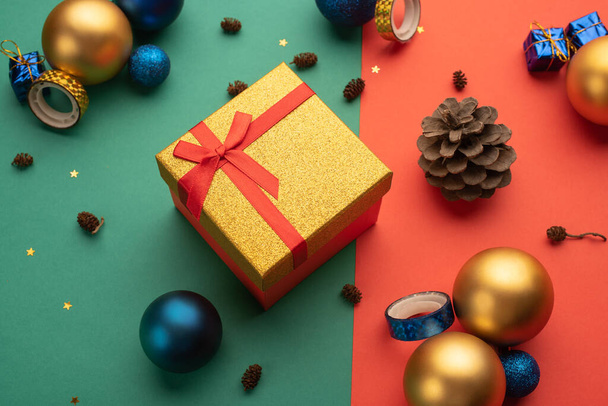Christmas composition with cones, Christmas balls and a gift box on bright two-colored background - Fotoğraf, Görsel