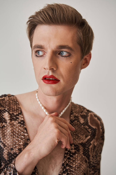 Drag performer with bright classic make up looking away and touching his neck - Φωτογραφία, εικόνα