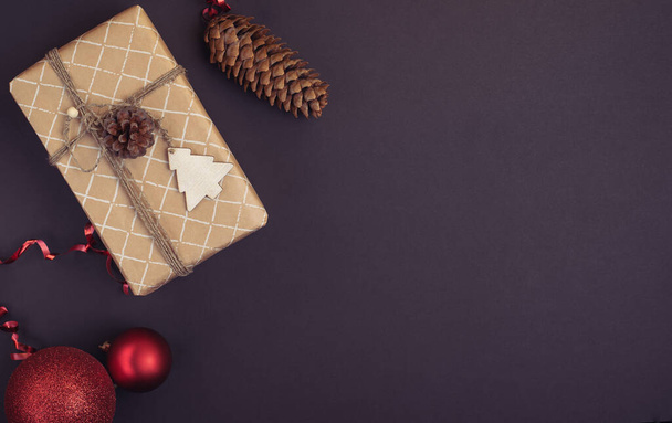 Christmas gift wrapped in craft paper and Christmas decoration on a dark background. Flat lay.  - Photo, Image